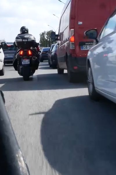 Une moto circule entre les voitures sur le périphérique