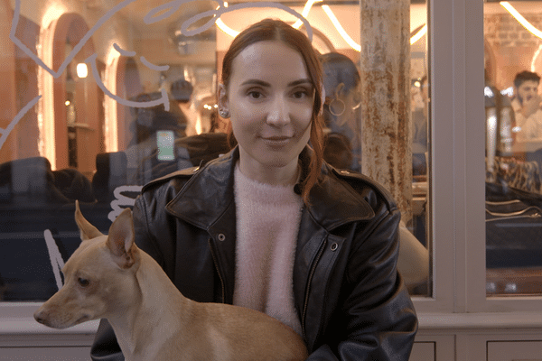 Natoo devant son coffee shop et salon de coiffure "Mousse" avec sa chienne Lola