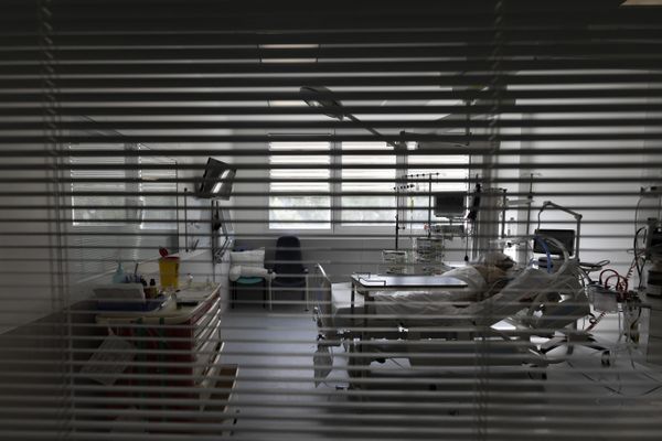 Un patient dans un lit d'hôpital, caché par des stores - Photo d'illustration