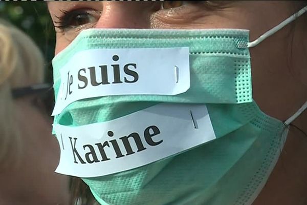 Une jeune femme porte un masque médical "Je suis Karine", lors de la marche blanche. 