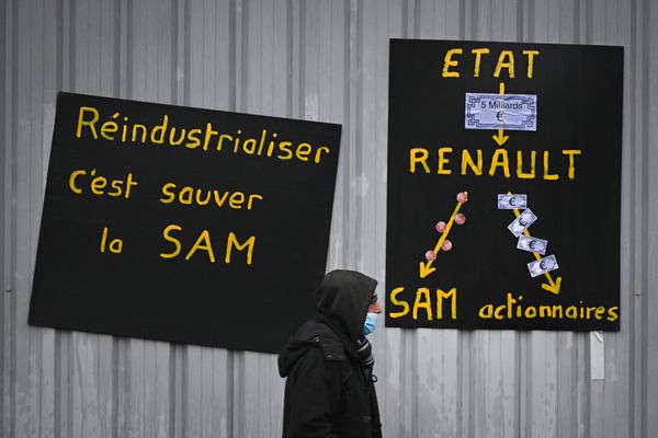 Un homme marche devant des pancartes dénonçant la cessation d'activité de la SAM (Aveyron), le 24 novembre 2021.