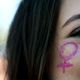 Un symbole de vénus sur la joue d'une jeune femme durant une manifestation féministe. 