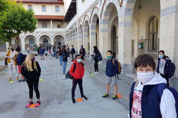 Les élèves masqués attendent sur un plot que leur professeur vienne les chercher