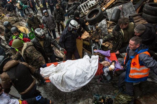 Des opposants portent un homme blessé lors des affrontements avec la police à Kiev