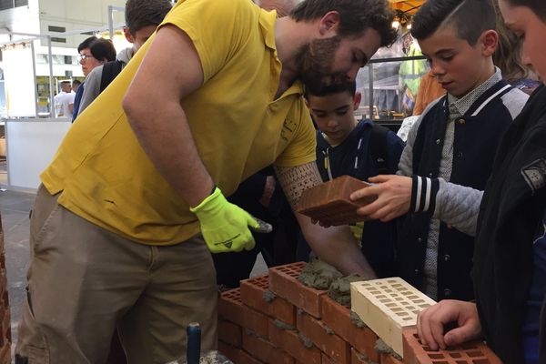 Des jeunes visiteurs bâtissent un mur aux Olympiades des Métiers. 