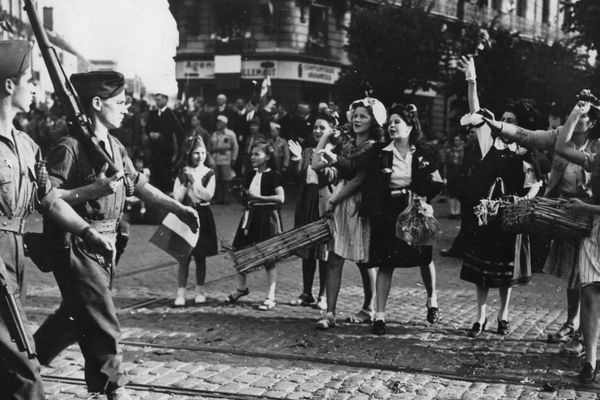 Des jeunes filles et des enfants jettent des fleurs aux soldats de la 1ere Armee française qui viennent de libérer la ville de Dijon. Photographie 11 septembre 1944.