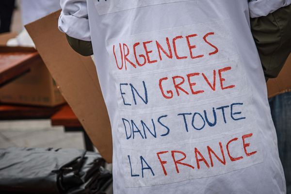 Un soignant arbore sur sa blouse le slogan "Urgences en grève dans toute la France". 