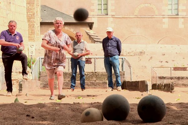 Pour remporter le point, Christiane doit lancer sa boule de bois au plus près du cochonnet, soit la boule claire.