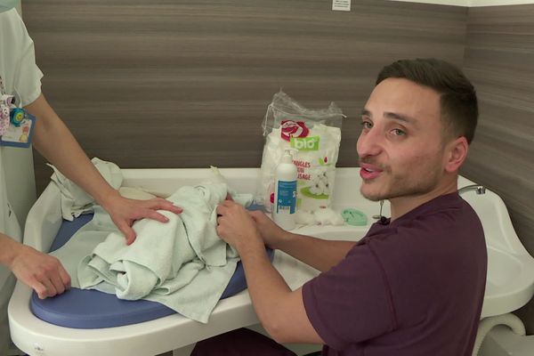 Devant la table à langer, Yann suit les conseils d'une infirmière pour s'occuper de sa petite fille.