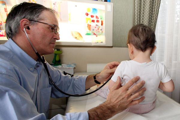 Un pédiatre lors d'une auscultation dans son cabinet.