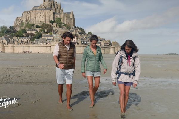 Clémence, Marc et leur guide Anne-Laure pataugent en direction des sables mouvants de la baie du Mont-Saint-Michel.