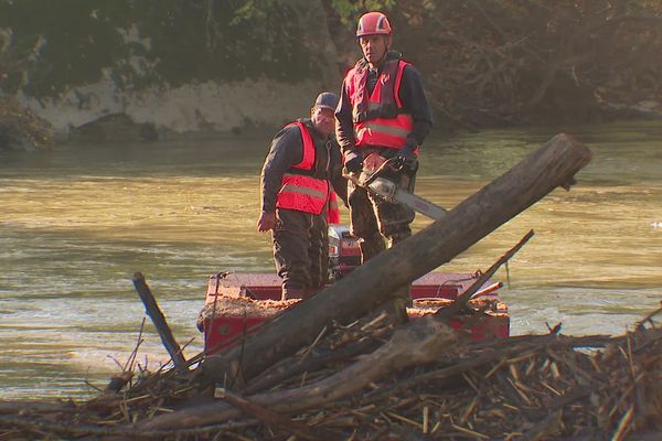 Une équipe intervient pour enlever l'embâcle qui obstrue le cours d'eau au niveau d'un pont.