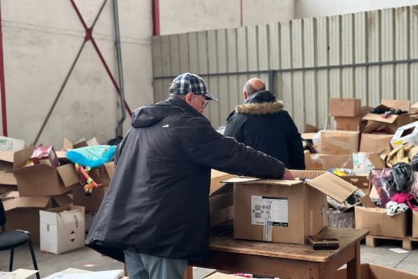 Jean-Michel Monnet-Paquet, secrétaire général du Secours populaire Portes de l'Isère, en train de trier les vêtements dispersés dans le local.