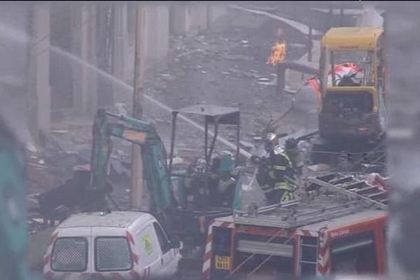 Un pompier éteint l'incendie dans un paysage dévasté par le souffle de l'explosion.  