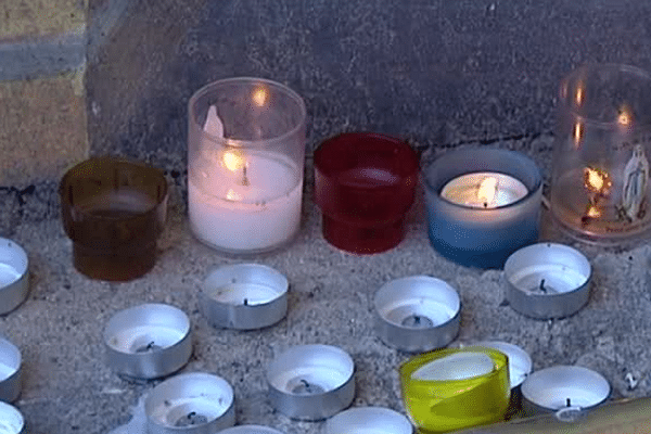 Des bougies et des fleurs, devant la boulangerie où la victime a été retrouvée. 