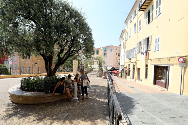 Des passants assis à l'ombre d'un arbre dans la vieille ville de Menton, durant l'été 2022.