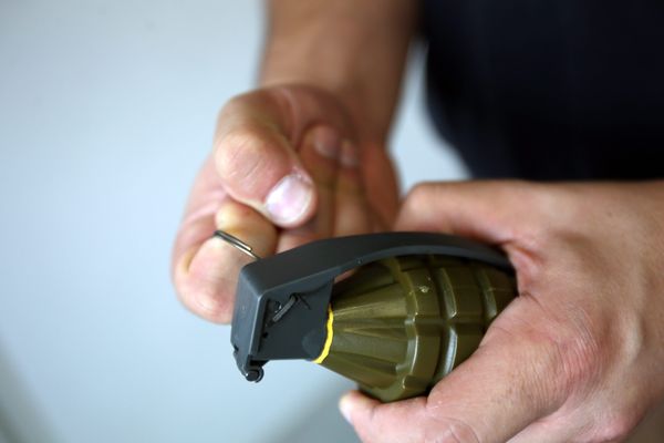 Un homme mimant de dégoupiller une réplique de grenade (illustration).