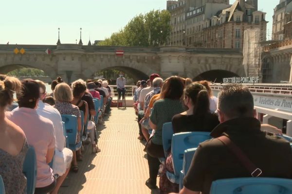 Des touristes à bord d’une vedette, sur la Seine.