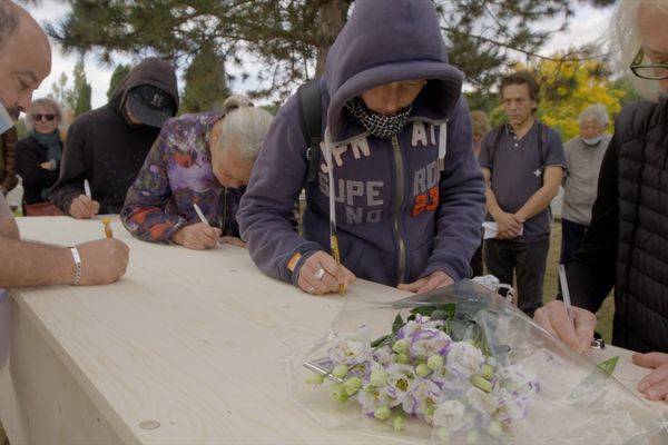 Des bénévoles sensibilisés par l’injustice sociale et l’exclusion se mobilisent pour offrir de vraies sépultures aux morts de la rue. Ici, chacun écrit un mot, une attention, sur un cercueil pendant des obsèques.