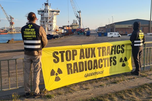 Des militants de Greenpeace devant le port de Dunkerque, ce vendredi 29 octobre 2021. En arrière plan, les 20 conteneurs remplis d'uranium en partance pour la Russie.