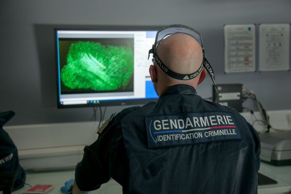 Un gendarme de l'identification criminelle recherche des empreintes collectées sur un paquet de résine de cannabis. Photo d’illustration.