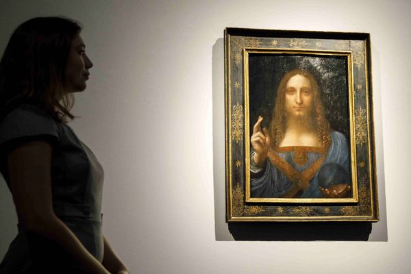 Une employée de Christie's pose devant la peinture Salvator Mundi de Léonard de Vinci at a photocall, à la vente aux enchères Christie's de Londres, le 22 octobre 2017, avant la vente de New York programmée le 15 novembre