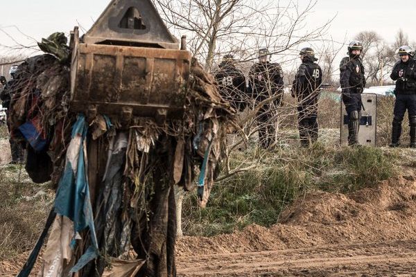 Des travaux de défrichement de la "Jungle" de Calais sous le regard des forces de l'ordre.