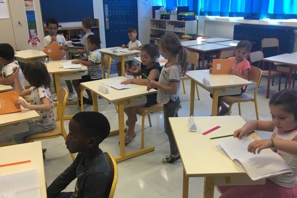 Plusieurs élèves assis à leur table dans leur classe.