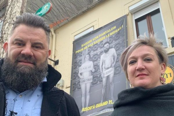 Derrière Yann Malet et son épouse Mathilde, une affiche les présentant nus, accrochée sur la façade de leur café à Outreau