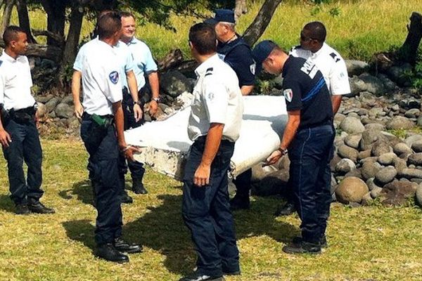 Policiers et gendarmes évacuent un morceau d'aile d'avion retrouvé sur le littoral de Saint-André à la Réunion, le 29 juillet 2015.