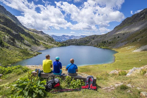 Des randonneurs contemplent un lac de montagne.