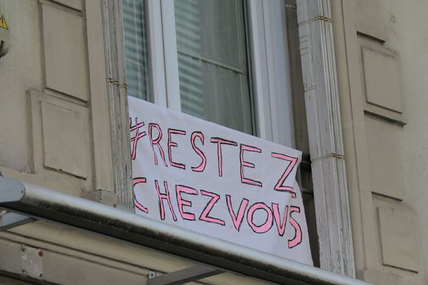 Un écriteau " Restez chez vous " posé sur une fenêtre à Paris.