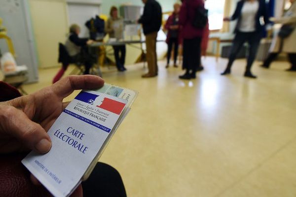 Un homme tient sa carte électorale dans un bureau de vote 