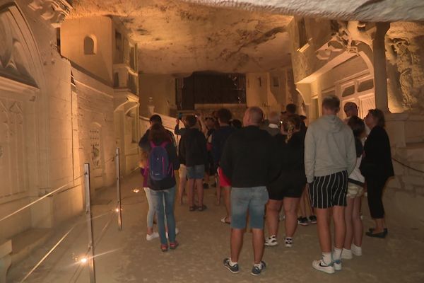 Touristes visitant la ville souterraine sculptée dans la pierre de tuffeau de la Cave des Roches