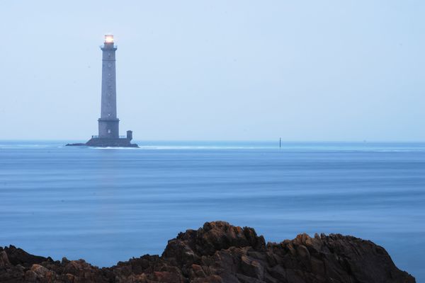 Dans le Cotentin, à l'horizon de la Hague, mer calme au crépuscule vers le phare de Goury.