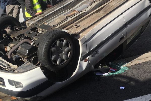 La Peugeot 306 de Cécile et Boris, sur le toit, avec divers effets personnels éparpillés parmi les éclats de verre.