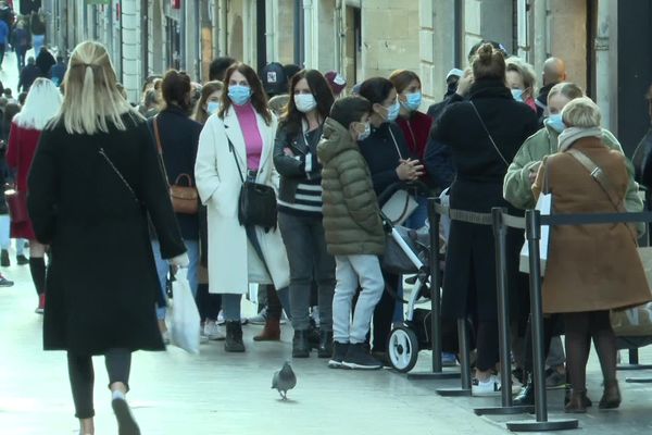 Les acheteurs patientent masqués avant de pouvoir pénétrer dans les boutiques, rue Sainte-Catherine à Bordeaux. 