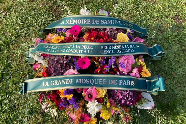 La gerbe de fleurs déposée ce vendredi matin par la grande mosquée de Paris devant le collège du Bois d'Aulne, "à la mémoire de Samuel Paty" : "L’ignorance mène à la peur, la peur mène à la haine, et la haine conduit à la violence. Averroès".