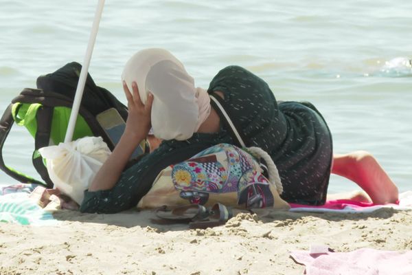 Vacancière voilée de dos sur la plage du Grau-du-Roi en août 2024 - Illustration.