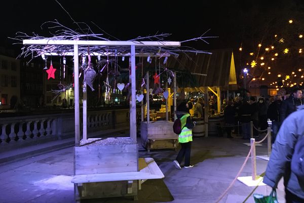 Une zone alimentaire dédiée (Zad) sur la terrasse Rohan, vide, avec plein de gens serrés consommant leur vin chaud devant le comptoir d'un chalet, en arrière-plan.