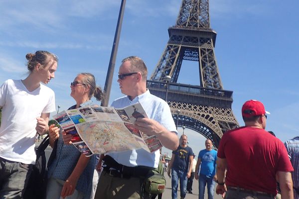 Des touristes au pied de la tour Eiffel, à Paris.