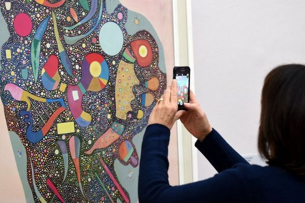 Un visiteur photographie une toile intitulée "Entassement regle" exposée dans le cadre de "Kandinsky, les années parisiennes" au Musée de Grenoble. 
