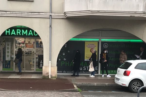 Dans le centre-ville de Bruges, les clients de la pharmacie font la queue tout en respectant les distances de sécurité