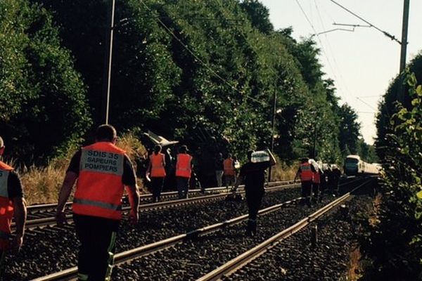 Des personnels de la SNCF apportent de l'eau aux passagers d'un TGV et inspectent les voies, suite à la collision entre une rame et les débris d'un tracteur sur la voie.