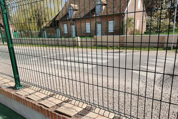 Des enveloppes remplies d'exercices le long du muret de l'école.