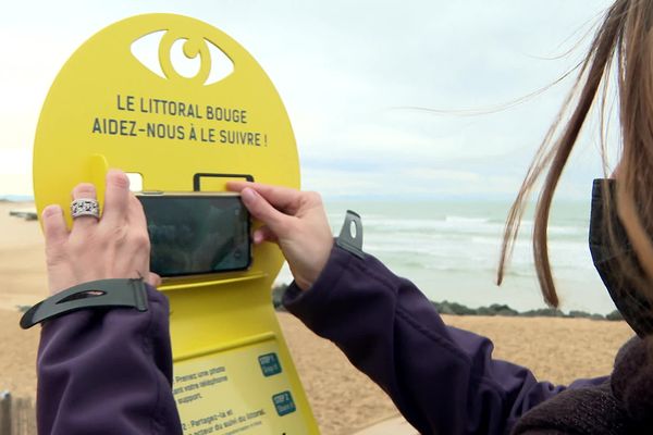 Une promeneuse participe au projet CoastSnap à Capbreton dans les Landes en prenant une photo du littoral.