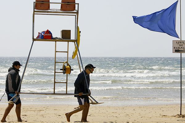 Deux CRS maître-nageur-sauveteurs (MNS) déplacent leur mirador vers la zone de baignade surveillée, le 04 juin 2006 sur la plage de Lacanau, alors que la station balnéaire vient de recevoir le pavillon bleu 2006