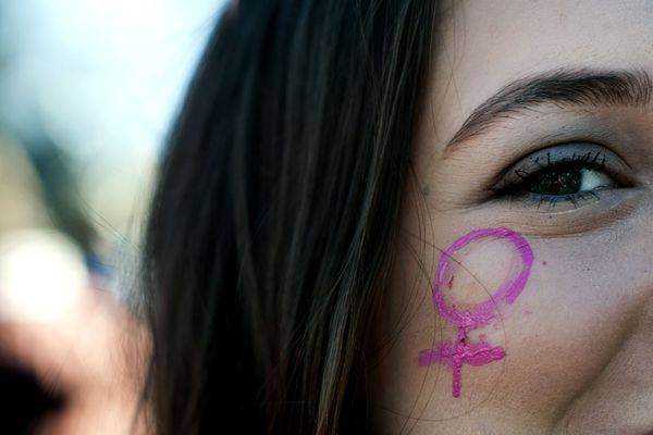 Un symbole de vénus sur la joue d'une jeune femme durant une manifestation féministe. 